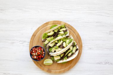 Mısır ekmeği ızgara sığır eti, avokado, kireç ve salsa ahşap tahta üzerinde yukarıda. Üstten görünüm. Kopya alanı.