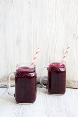 Berry yüzlü beyaz ahşap arka planda, yan görünümü ile cam kavanozlar. Metin için yer.