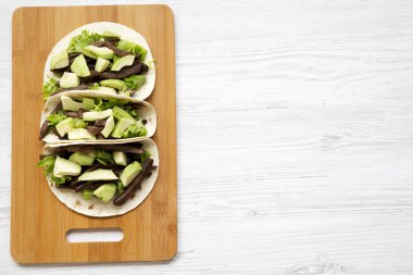 Ekmeği ızgara sığır eti ve avokado Beyaz ahşap zemin üzerinde bambu gemide. Görünümü, yukarıdan, ek yükü üst. Metin için yer.