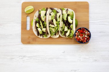 Mısır ekmeği ızgara sığır eti, avokado, kireç ve salsa ahşap tahta üzerinde. Yukarıdan. Kopya alanı.