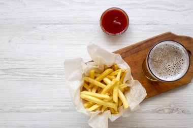 Patates kızartması, ketçap ve soğuk bira Beyaz ahşap zemin üzerinde yukarıdan görüntüleyin. Üstten görünüm, ek yükü. Kopya alanı.