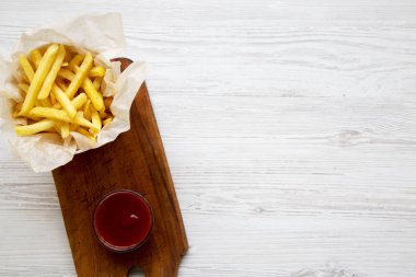 Ahşap tahta ketçap ile kızarmış patates yukarıda. Beyaz ahşap arka plan. Kopya alanı.