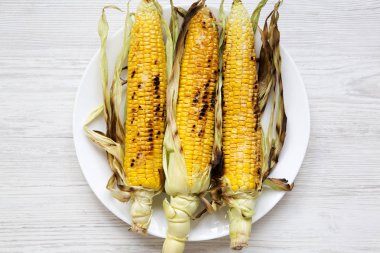 Bir tabakta beyaz, ek yükü üzerinde ızgara Mısır. Üstten görünüm, düz-lay. 