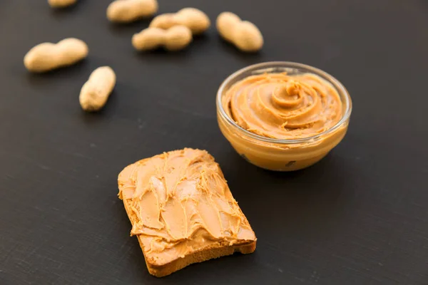 Tigela Manteiga Amendoim Amendoins Sem Casca Sobre Fundo Preto Vista — Fotografia de Stock