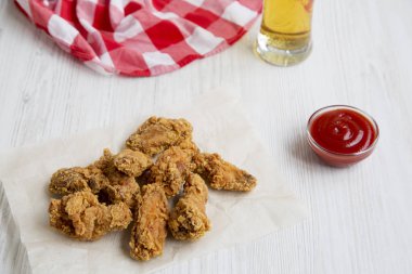 Taze kızarmış tavuk kanadı kırmızı biber sosu, soğuk bira ve peçete. Yan görünüm.