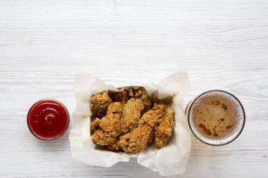 Soslu tavuk kanatları, bir beyaz tahta masada soğuk bira yukarıdan görüntüleyin. Düz lay, ek yükü. Kopya alanı.