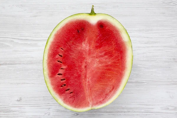 Beyaz ahşap yüzey, en iyi görünümü üzerinde yarım düzenlenen karpuz. Yukarıdan.