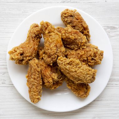 Beyaz ahşap yüzey üzerinde kanatları beyaz yuvarlak tabakta tavuk, yukarıdan görüntüleyin. Üstten görünüm, düz yatıyordu.