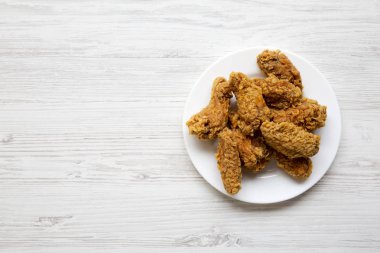 Beyaz ahşap arka plan üzerinde kanatları beyaz yuvarlak tabakta tavuk, yukarıdan görüntüleyin. Düz-lay, genel gider. Kopya alanı.