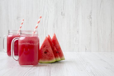 Cam kavanoz karpuz güler yüzlü beyaz ahşap zemin, yan görünüm üzerinde. Kopya alanı.