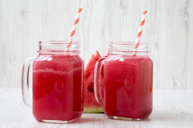 Cam kavanoz karpuz güler yüzlü beyaz ahşap yüzey, yan görünüm üzerinde. Portre.