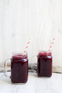 Berry yüzlü beyaz ahşap yüzey, yan görünümü ile cam kavanozlar. Uzay kopyalayın. Portre.