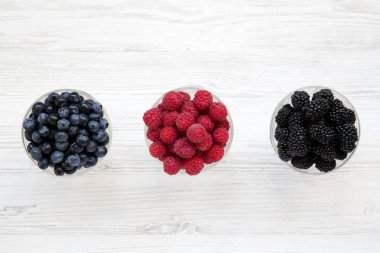 Meyveleri içeren kase: yaban mersini, böğürtlen, ahududu, üstten görünüm. Sağlıklı beslenme. Yukarıda, ek yükü.