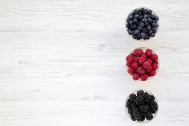 Yukarıdan, meyveleri içeren kase: yaban mersini, böğürtlen, ahududu. Sağlıklı beslenme ve diyet. Yukarıda, ek yükü. Metin için yer.