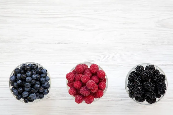 Meyveleri içeren kase: yaban mersini, böğürtlen, ahududu, üstten görünüm. Sağlıklı beslenme ve diyet. Yukarıda, ek yükü. Kopya alanı.