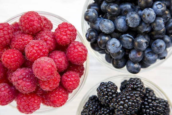 Tam kaseler yaban mersini, böğürtlen, ahududu, yukarıdan görüntüleyin. Sağlıklı beslenme ve diyet. Üstten görünüm, ek yükü. Portre.