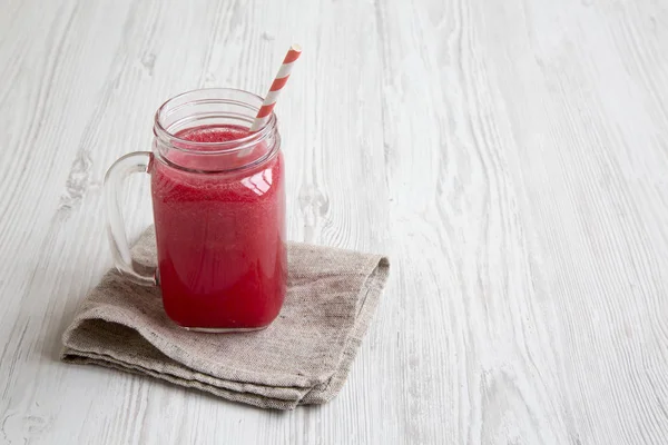 Cam kavanoz karpuz güler yüzlü beyaz ahşap bir masa yan görünüm üzerinde. Boşluk ve metin alanı Kopyala.