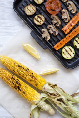 Beyaz ahşap zemin, üstten görünüm üzerinde limon dilimleri ile ızgara sebze. Yukarıdan, ek yükü yat.