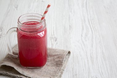 Cam kavanoz karpuz güler yüzlü beyaz ahşap zemin, yan görünüm üzerinde. Kopya alanı.