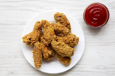 Beyaz ahşap arka plan üzerinde kırmızı biber ile yuvarlak beyaz tabakta tavuk kanadı sosu yukarıdan görüntüleyin. Tepegöz, yatıyordu, en iyi görünüm düz. Portre.