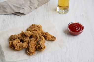 Soslu taze kızarmış tavuk kanatları, Beyaz ahşap yüzey, yan görünüm üzerinde soğuk bira. 