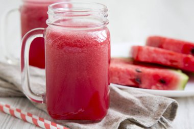 Cam kavanoz karpuz güler yüzlü beyaz ahşap zemin, yan görünüm üzerinde. Portre.