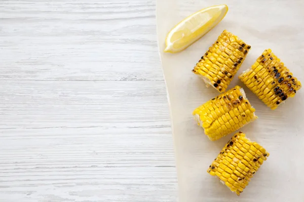 Grilled corn on the cob on a white wooden background. Summer food. From above, overhead. Copy space.