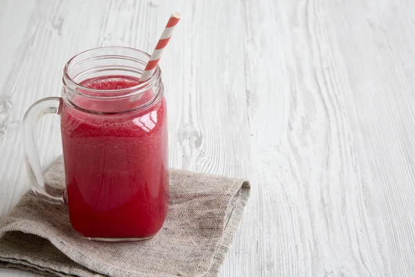 Cam kavanoz karpuz güler yüzlü beyaz ahşap zemin, yan görünüm üzerinde. Kopya alanı.