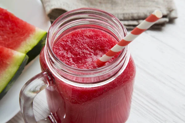 Karpuz yüzlü beyaz ahşap bir masa portre üzerinde cam kavanoz.