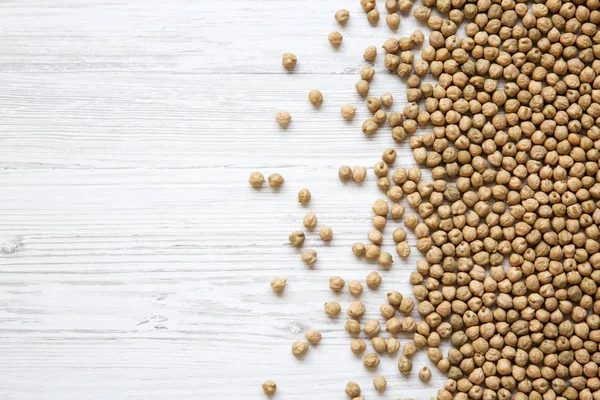 Üstten görünüm, Beyaz ahşap zemin üzerinde kuru nohut. Kopya alanı.