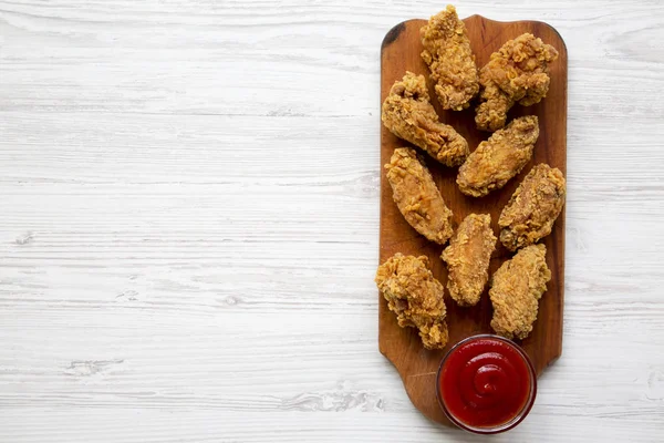 Görünümü en çok, kanatları sos ile ahşap bir tahtada beyaz ahşap arka plan üzerinde tavuk. Kopya alanı.