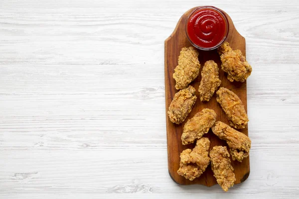 Yukarıda, Beyaz ahşap arka plan üzerinde kırmızı biber sosu ile ahşap bir gemide kanatları tavuk. Metin alanı ve kopya alanı.