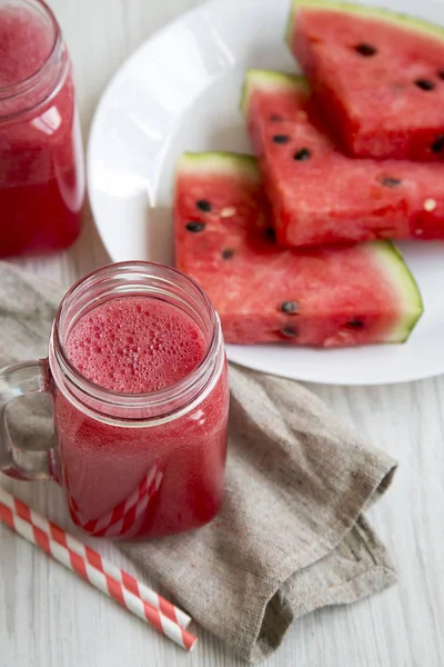 Cam kavanoz karpuz güler yüzlü beyaz ahşap zemin, yüksek açı üzerinde.