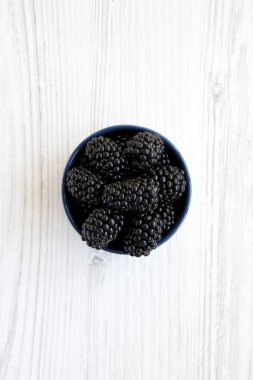 Yukarıdan bir beyaz ahşap yüzeyde olgun böğürtlen mavi kase tam. Yaz meyve. Yukarıda, ek yükü. 