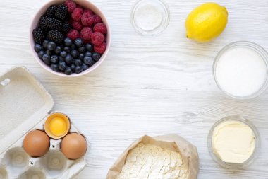 Çerçeve maddeler berry pie üstten görünüm beyaz tahta masada yemek pişirmek için. Düz lay, ek yükü. Kopya alanı.