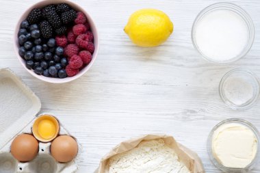 Çerçeve berry pie Beyaz ahşap zemin üzerinde yemek pişirmek için ham maddeler yukarıdan görüntülemek. Düz lay, ek yükü. Kopya alanı.