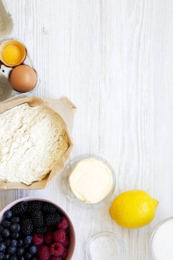 Yukarıda, Beyaz ahşap zemin üzerinde pasta yemek pişirmek için ham maddeler berry. Düz lay, ek yükü. Kopya alanı.