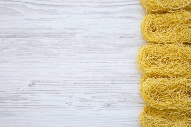 Düz pişmemiş makarna tagliolini Beyaz ahşap yüzey üzerinde yatıyordu. Üstten görünüm, ek yükü. Kopya alanı.