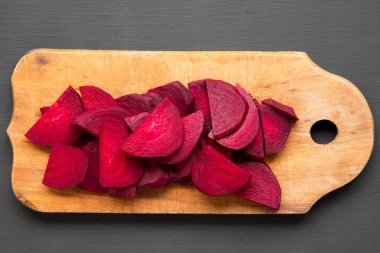 Siyah arka plan, üstten görünüm üzerinde Ahşap Doğrama tahtası üzerinde doğranmış kırmızı pancar. Portre. Yukarıdan, tepegöz, düz yatıyordu.