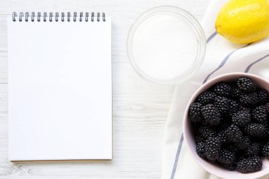 Beyaz ahşap masa, üstten görünüm üstünde boş defter ile böğürtlen için malzemeler reçel. Yukarıda, ek yükü.