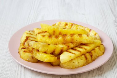 Ananas dilimleri pembe plaka üzerinde beyaz ahşap arka plan üzerinde yan görünüm ızgara. Yaz yiyecek. Aperatif için fikir. Portre.