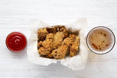 Ketçap ile tavuk kanatları, bir beyaz tahta tablosundan, yukarıdaki soğuk bira. Düz lay, ek yükü. Portre.