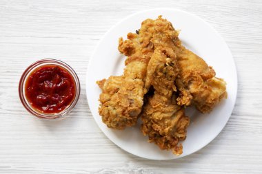 Kızarmış tavuk drumsticks bir beyaz üzerine ketçap, üstten görünüm plakalı yuvarlak. Yukarıdan, tepegöz, düz yatıyordu.