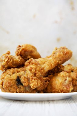 Kızarmış tavuk budu üzerinde beyaz bir levha, closeup yuvarlak. Yan görünüm.