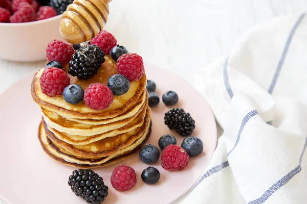 ベリーとピンク プレート 側面図の上に蜂蜜のおいしいパンケーキ クローズ アップ — ストック写真
