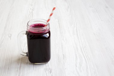 Cam kavanoz kupa düşük açılı Beyaz ahşap arka plan üzerinde kırmızı pancar güler yüzlü. Kopya alanı.