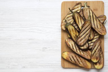 Üstten görünüm, Bambu tahta üzerinde beyaz ahşap yüzey üzerinde ızgara patlıcan. Kopya alanı.