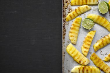 Tepsi, düz siyah arka plan üzerinde limonlu ızgara ananas yatıyordu. Yukarıdan, tepegöz, görünümü top. Boşluk ve metin alanı Kopyala.