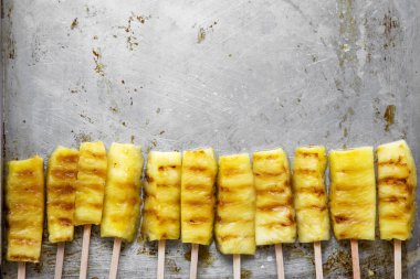 Bambu üzerinde ızgara ananas düz lay tepsi üzerinde sopa. Kopya alanı.