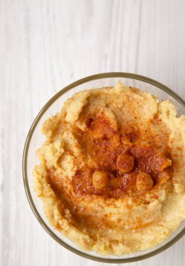 Humus leblebi ile kase, kırmızı biber ve zeytinyağı üzerinde beyaz ahşap bir masa üstten görünüm içinde. Yukarıdan, ek yük düz lay.